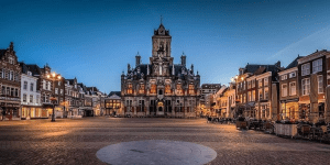 A picture of the Market Square in the city of Delft at dusk, showing the historic City Hall building, a famous landmark 