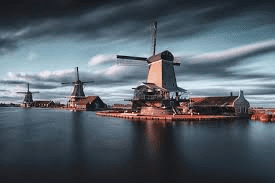 An artistic picture of historic windmills on the water, showing a side of the charm of tourism in the Netherlands.