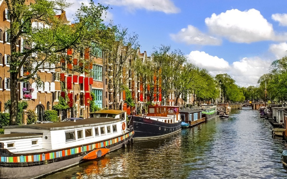 A picture of a beautiful canal in Amsterdam lined with traditional houses and boats, reflecting the charming atmosphere of tourism in the Netherlands.
